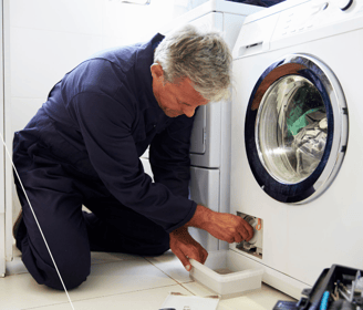 a man in a blue shirt is fixing a washing machine