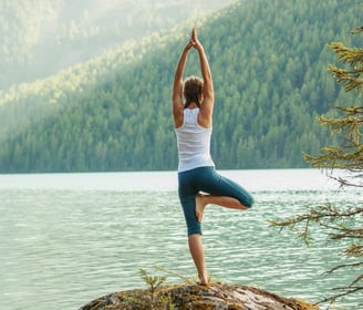 a woman doing yoga exercises on a rock