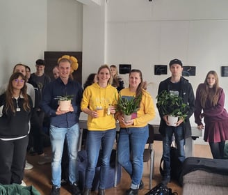 Orchidėjų laboratorijos renginio dalyviai sustoję kartu su lektore Vilte. Rankose laiko orchidėjas.