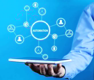 Man in blue shirt holds up a tablet with a holographic mind map centred on "Automation" emerging from the screen, face unseen