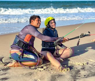 professor de kitesurf dando aula para uma mulher jovem em frente a praia.
