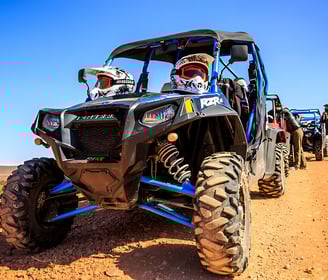 a group of people riding a quad bike buggy on a dirt road in the desert