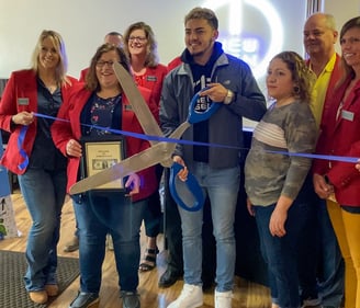 a group of people holding scissors and cutting a ribbon