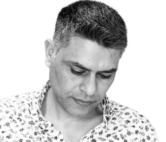 black and white photo of author and poet Himayath Khan in a floral shirt looking down