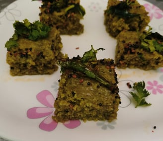a plate with four pieces of Green healthy dhokla  on it
