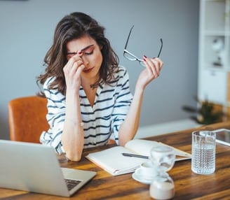 a woman with glasses and a laptop computer sitting at a table