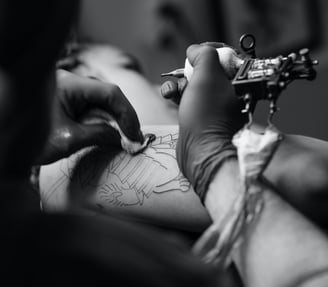Artista tatuando um cliente com uma máquina de tatuagem.