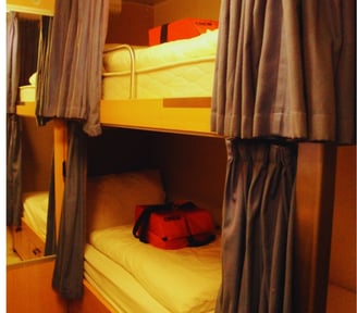 Primeira cabine da autora a bordo, com cama, TV e telefone, oferecendo conforto básico para descanso