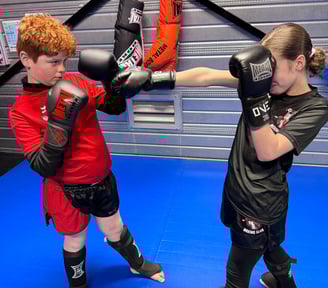 Boxe éducative : une jeune fille enchaîne des coups de poing face à un garçon en garde