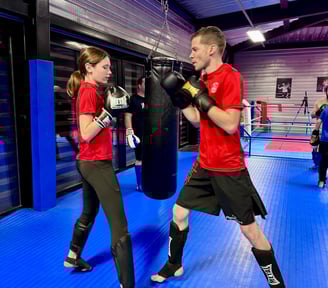 Entraînement de boxe : un homme et une jeune fille en garde, prêts à boxer