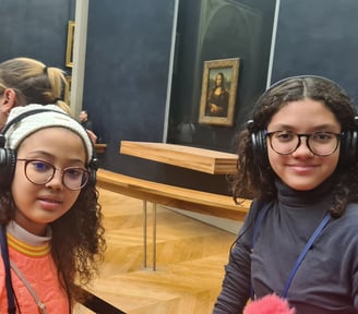 Duas adolescentes com autoguia em frente a obra de arte Monalisa no museu Louvre em Paris