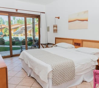 quarto com cama, luminarias e vista para o jardim
