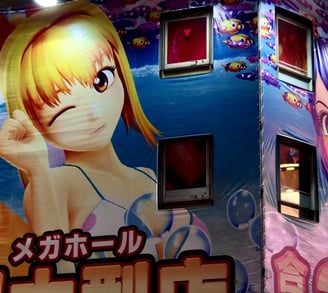 An illuminated building facade is covered with large, colorful anime-style illustrations featuring c