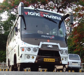 A white color bus with name written on it along with registration number.