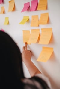 a person holding a piece of paper with sticky notes on it