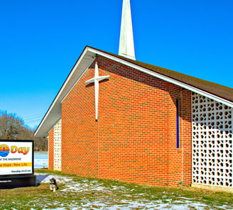 Our church with our new sign, photobombed by the Pastor's dog, Scamp.