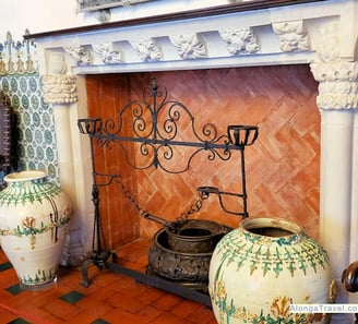 an ornately decorated brick and plaster Mudejar fireplace surrounded by Moorish ceramic tiles