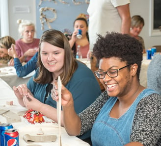 Individuals at a private party laughing as they begin their clay project.