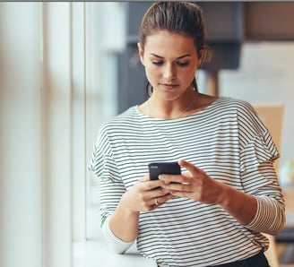 a woman in a striped shirt is looking at her phone