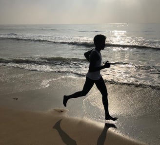 a person running on a beach near the ocean