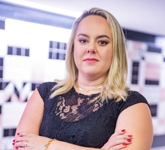 uma mulher loira de meia idade com vestido preto e esmalte vermelho nas unhas.