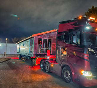 a truck with a trailer parked in front of a building. double lodge. eps panel. portable. affordable.