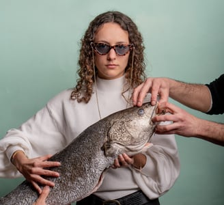 fotografía corporativa de gastronomia de una mujer sosteniendo un pez con gafas de sol