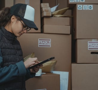 a woman in a black jacket and a hat with a tablet on a table