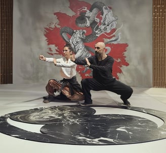 Ismet Himmet and Gizem Kara practicing a Tai Ji form on a yin-yang mat before a dragon mural.