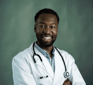 Médico negro sorrindo, com estetoscópio no pescoço e braços cruzados.