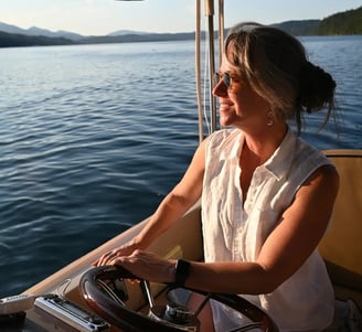 a beautiful woman in a white shirt is sitting on a eco-friendly electric boat cruising hood canal