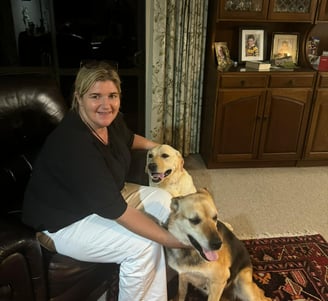 a woman sitting on a couch with two dogs