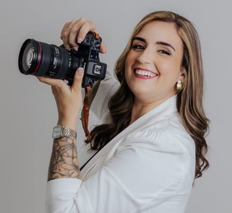 a woman holdingDébora Oliveira fotógrafa de casamentos no Rio de Janeiro a camera and smiling