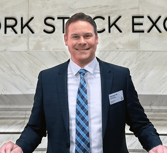 a man in a suit and tie standing in front of a sign that says new