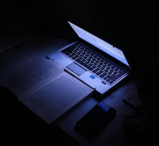 a laptop computer sitting on a desk with a cell phone and a cell phone