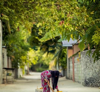 a woman in a pink dress is cleaning a sidewalk