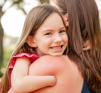 Young smiling girl with arm that stops at wrist hand and hugging a woman 