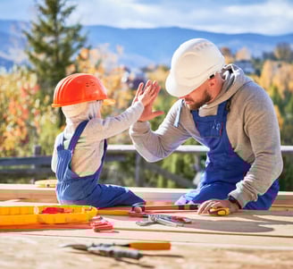 Un père et son fils en tenu de travail se tapant la main