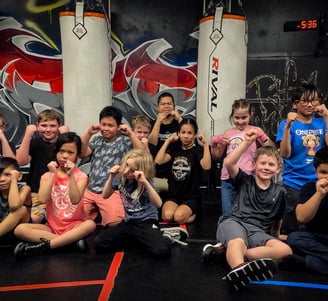 a group of children and the coach posing with their fists raised