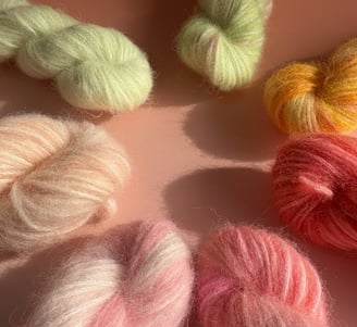 Håndfarvede garnfed i klare og pastelfarver – mohair, silke og merinould i orange, pink og blå.