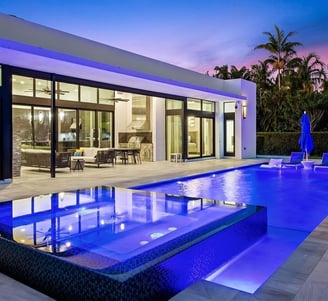 a fiberglass pool in a backyard with blue lights and a spa with infinity edge to the swimming pool