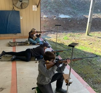 a man and woman are shooting rifles in a shooting range