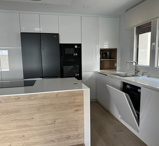  Cocina blanca y madera, isla central, electrodomésticos negros integrados.