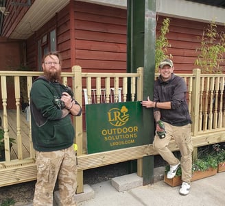 two men standing next to a sign that says outdoor