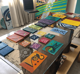 glass table covered in Yous’ small paintings