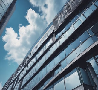 A modern office building with a geometric, pyramid-shaped top. The architecture features reflective glass windows and a beige stone exterior. The name 'Mutua Madrileña' is displayed near the top.