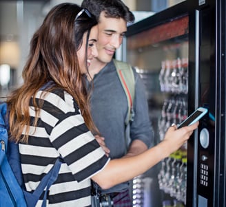 A couple usint tap to pay to make a vending machine purchase
