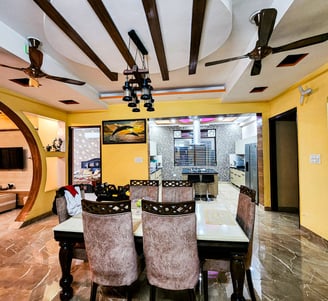 A stylish dining area with wooden beams, decorative lighting, and an open kitchen layout.