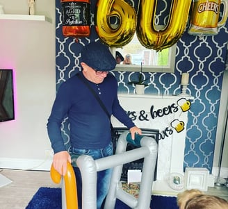 A picture of Rob Hamilton on his 60th birthday, holding an inflateable zimmer frame