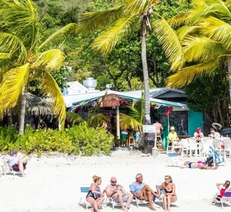 Guests sitting in beach chairs on the white sands outside The Soggy Dollar in BVI
